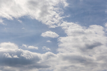 A tranquil view of a blue sky filled with scattered white and gray clouds on a bright day.