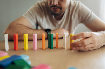 Man playing with colorful dominoes on a table indoors