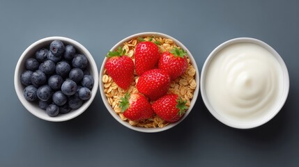 Top view of yogurt bowl ingredients including granola and berries, prepped with light space