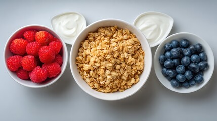 Top view of yogurt bowl ingredients including granola and berries, prepped with light space