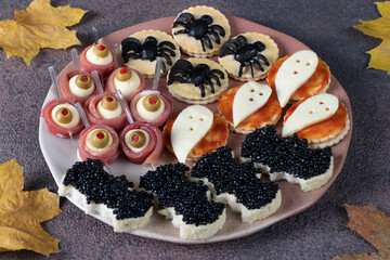 Salty snacks for Halloween party on brown background