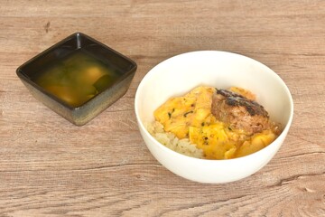 grilled hamburg pork steak and creamy egg omelets topping on rice in bowl with miso or soy sauce...