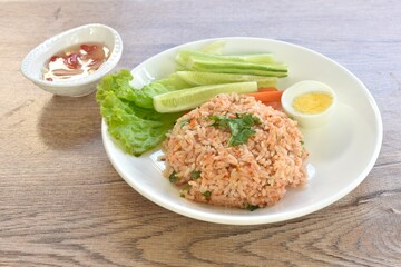 spicy fried rice with mashed salmon topping half boiled egg eat couple fresh vegetable on plate dressing slice chili and garlic fish sauce 