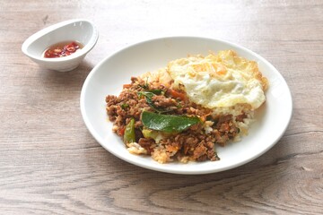 spicy fried chop meat in herb curry topping on plain rice with egg on plate dressing chili fish sauce 