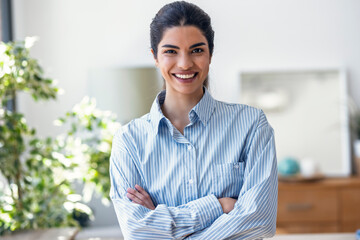 Smiling female customer service representative in an office with arms crossed