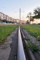 Fototapeta premium Close-up of tram rails with green grass bokeh, Urban transportation infrastructure macro detail.