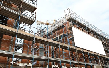 Blank information board on the facade of a new large building under construction among the...