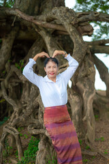Asian women in traditional poses.Laos girl in traditional dress against a backdrop of trees.