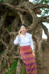 Asian women in traditional poses.Laos girl in traditional dress against a backdrop of trees.