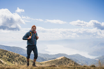 Happy man hiking on mountain in front of cloudy sky