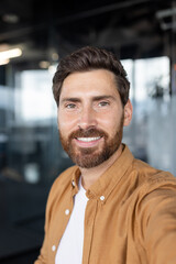 Young successful businessman looking into phone camera, using smartphone app for video call,...