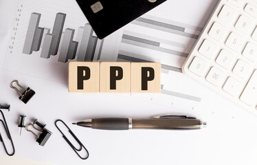 PPP abbreviation on wooden blocks with financial charts, credit card, calculator and office supplies