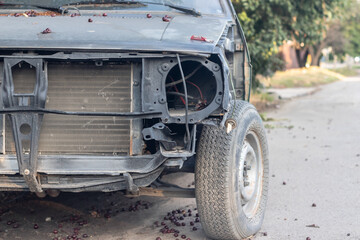 A damaged car is abandoned on a city street.