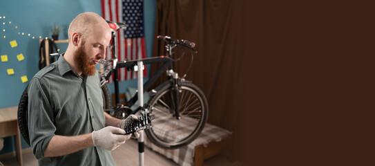 Bearded man repairing bicycle against american flag background at home choosing wrench from set....