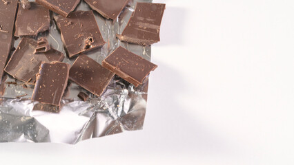 A foil wrapper with chocolate pieces on it. The foil wrapper is crumpled and the chocolate pieces...