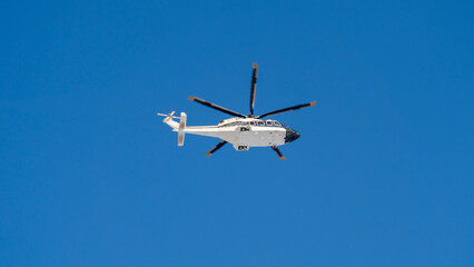 white helicopter flying in the blue sky from a close-up perspective on the ground. A beautiful...