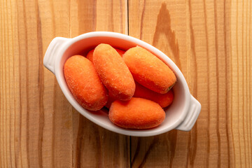 Mini carrots, peeled, with household utensils, macro, top view.