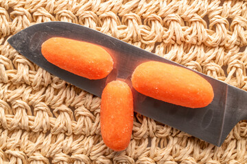 Mini carrots, peeled, with household utensils, macro, top view.