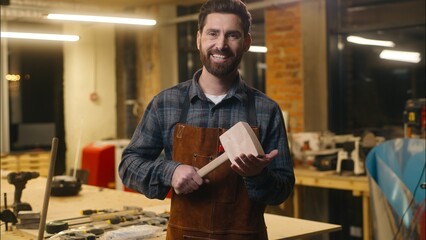 Happy Caucasian craftsman wood master man worker hold wooden hammer profession male artist work...