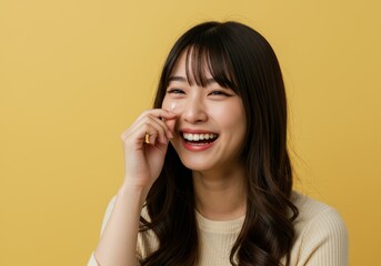 Fototapeta premium Joyful Young Woman Applying Skincare, Smiling Brightly Against Yellow Background