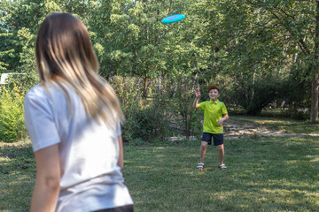 Female and her son are playing with frisbee in public park