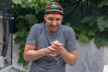 A middle-aged man wearing a bandana holds his pet rat