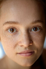 Close-up of calm young woman with freckles and soft natural skin under daylight. Concept of beauty,...