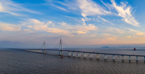 Aerial view of a modern cable stayed bridge stretching across the tranquil sea at sunset in Jiaxing, China.