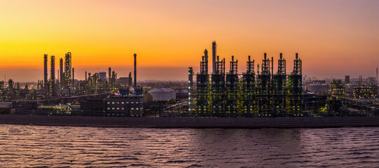 Oil refinery and petrochemical plant complex on the riverside with industrial equipment at sunset