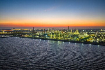 Panoramic view of an illuminated coastal oil refinery and chemical plant in industrial area