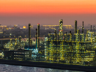 Illuminated oil refinery and chemical plant with industrial equipment at dusk