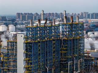Complex blue steel frame structure of a chemical plant with a city skyline in the background