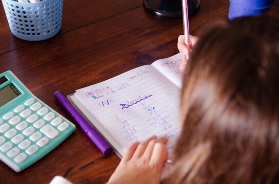 A young girl doing her maths homework using a calculator.