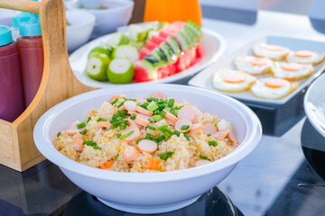 Traditional Thai breakfast with minced pork rice porridge, fresh vegetables, and fried eggs, beautifully served in white bowls and plates on a dining table