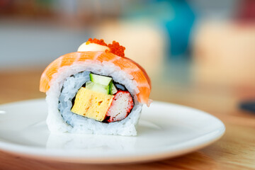 Fresh and colorful sushi roll with salmon, tamago, crab stick, cucumber, and rice, served on a...