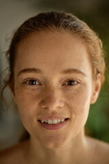 Close-up of cheerful young woman with glowing freckles and joyful expression. Concept of natural...