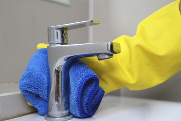 housekeeper is cleaning the faucet in the bathroom.