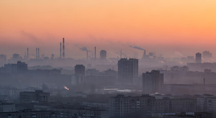 Obraz premium Industrial city skyline shrouded in smog at sunrise, showing pollution and urban density.