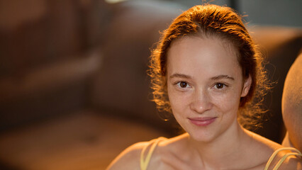 Smiling young woman with freckles looking at camera with warmth and calm expression. Concept of...