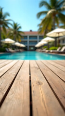 Fototapeta premium Wooden poolside terrace with tropical resort pool as backdrop, sun loungers and palm trees, sunny weather, relaxing summer vibes. Vertical image