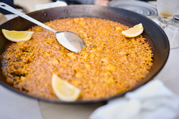 savory arroz a banda dish from Alicante served with squid and ladle in a paella pan at a coastal Mediterranean restaurant.
