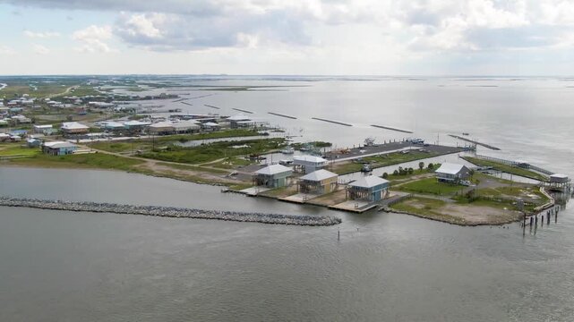 An aerial shot of the tip of Elmer's Island in Caminada Bay near Grand Isle, Louisiana. Includes breakwaters, coastal businesses, houses, and undeveloped land.