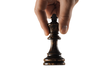 A hand carefully selects a black chess king piece.  Concept of strategy, leadership, and decision making.