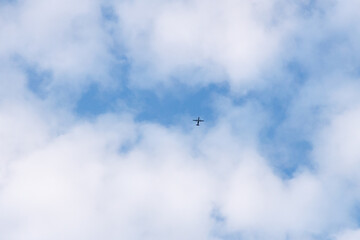 Airplane flying through the sky in far distance passing through the clouds