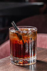 A refreshing glass of iced cola with dark soda, ice cubes, and dual black straws is served on a...