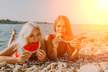Watermelon Beach Summer: Two women enjoy refreshing watermelon slices on a sunny beach.