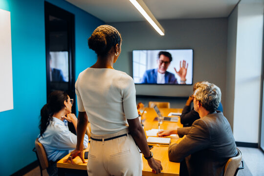 Team meeting with virtual participant displayed on an office screen