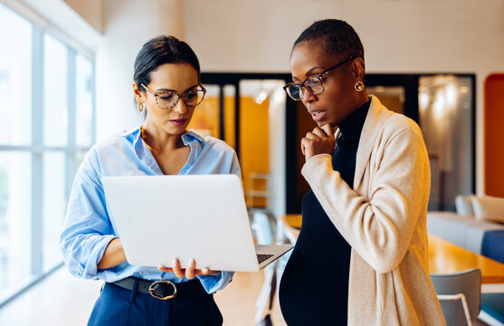 Two professionals working together discussing information on a laptop in an office