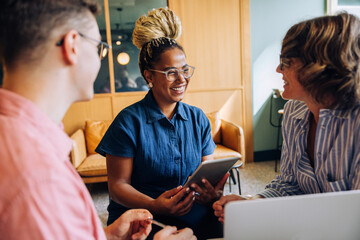 Colleagues having a cheerful discussion during a team meeting at the office