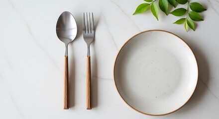 An empty plate with a spoon and fork on a marble surface